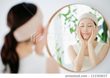 A woman checking the condition of her skin in the mirror 131569037