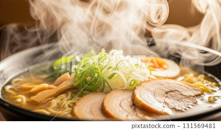 Steaming bowl of ramen with sliced pork, egg, and fresh scallions in warm broth 131569481