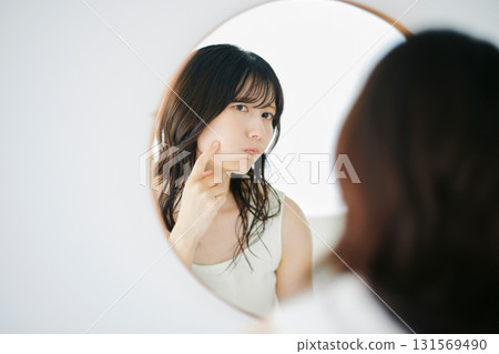 一個女人在鏡子裡檢查她的皮膚狀況 131569490