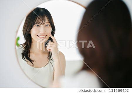 微笑的女人對著鏡子檢查自己的皮膚狀況 131569492