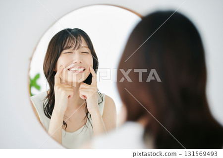 微笑的女人對著鏡子檢查自己的皮膚狀況 微笑的女人對著鏡子檢查自己的皮膚狀況 131569493