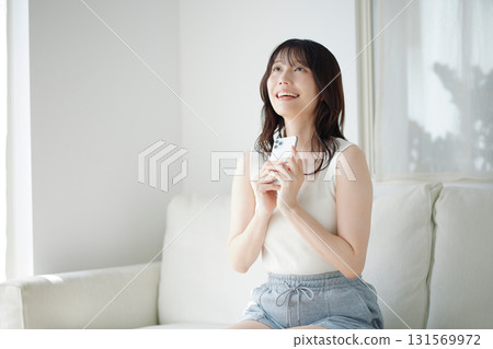 女人坐在沙發上，拿著一部智能手機 131569972