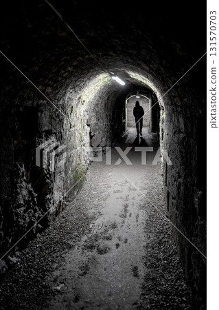 Silhouette Of A Single Person Walking Towards Door Through Dark Narrow Underground Aisle Spooky Illuminated By Neon Lights 131570703