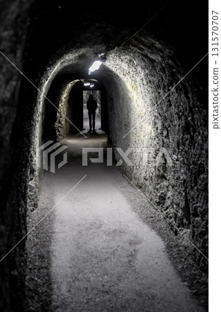 Silhouette Of A Single Person Walking Towards Door Through Dark Narrow Underground Aisle Spooky Illuminated By Neon Lights 131570707