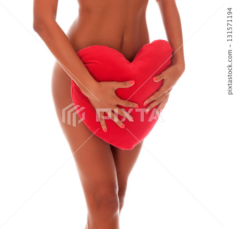 Closeup shot of slim tanned naked woman with heartshaped pillow isolated on white background Closeup shot of slim tanned naked woman with heartshaped pillow isolated on white background 131571194