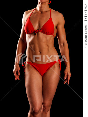 Sexy sports woman in red bikini posing against black background 131571202