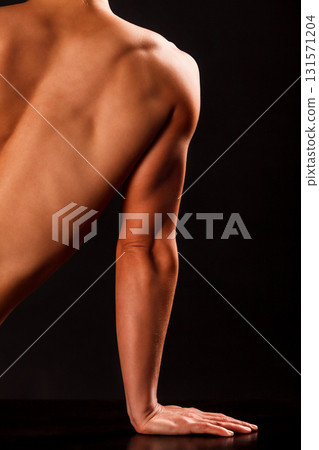 Arm and part of back of muscular woman posing against black background 131571204