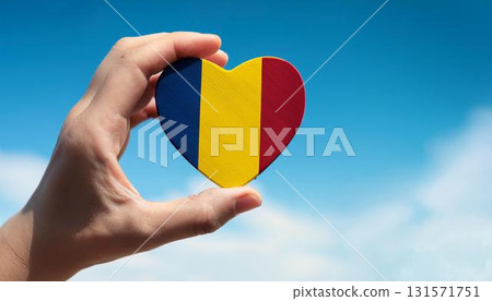 Romanian flag heart shape and blue sky held by hand 131571751