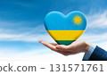 Heart shaped Rwandan flag held by hand against blue sky 131571761