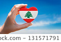 Lebanese flag heart shape and blue sky held by hand 131571791