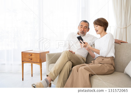 一對老年夫婦在沙發上放鬆並使用智慧型手機 131572065