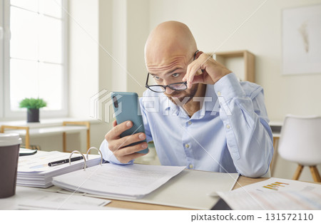 Serious Businessman Working In Office And Reading Online News On Smartphone 131572110