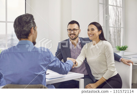 Happy couple shaking hands with a male business broker or insurance agent or investment adviser. 131572114