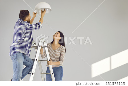 Happy loving couple changing light bulb in new apartment 131572115
