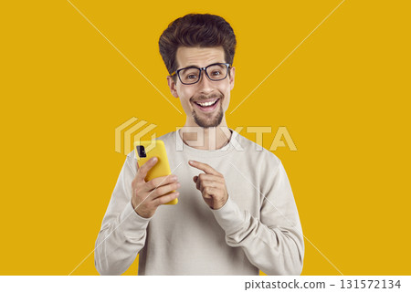 Portrait of young excited man pointing finger at smartphone screen 131572134