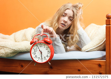 Unhappy woman waking up with alarm clock. Unhappy woman waking up with alarm clock. 131572375
