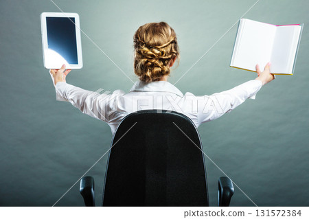 Woman holding traditional book and e-book reader 131572384