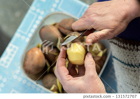 Closeup of woman hands peeling potatoes with a kitchen knife. Closeup of woman hands peeling potatoes with a kitchen knife. 131572707