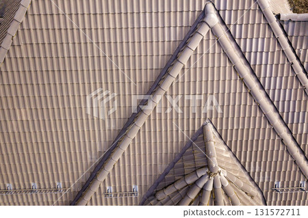Closeup of house roof top covered with ceramic shingles. Tiled covering of building 131572711