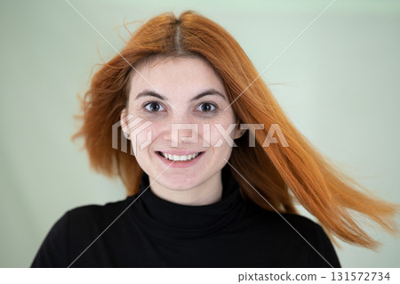 Close up portrait of pretty redhead girl with long wavy hair blowing on the wind. 131572734