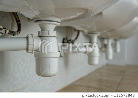 Close up of white plastic pipe drain under washing sink in bathroom. 131572948
