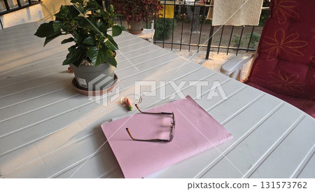 Cozy balcony setting with potted plant and glasses for relaxation and reading Horizontal banner. Copy space 131573762