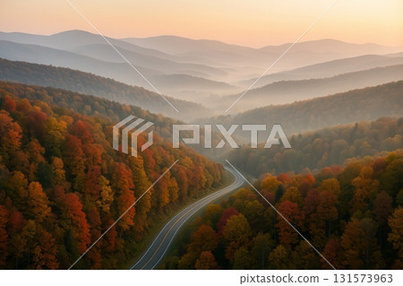 Scenic Autumn Forest with Curving Road and Misty Mountains 131573963