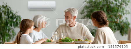 Happy family with grandparent and grandchild enjoying meal together. group eating at home while air conditioner provides comfort. moment of joy and togetherness Happy family with grandparent and grandchild enjoying meal together. group eating at home while air conditioner provides comfort. moment of joy and togetherness 131574103