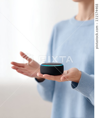 Focused woman holding smart speaker in hand. modern smart home device using voice assistant technology for convenient control and automation in home setting 131574468