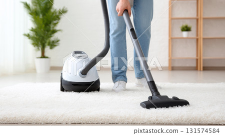 Person diligently cleaning white carpet in modern home with vacuum cleaner. domestic chore involves deep cleaning floor for good housekeeping and tidy routine Person diligently cleaning white carpet in modern home with vacuum cleaner. domestic chore involves deep cleaning floor for good housekeeping and tidy routine 131574584