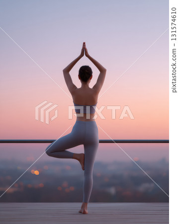 Serene young woman practicing yoga balance pose on city balcony at sunrise or sunset. peaceful and calm moment overlooking urban landscape with beautiful sky view Serene young woman practicing yoga balance pose on city balcony at sunrise or sunset. peaceful and calm moment overlooking urban landscape with beautiful sky view 131574610