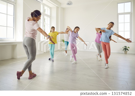 Happy children girls training modern dance moves together in studio with choreographer. Happy children girls training modern dance moves together in studio with choreographer. 131574852