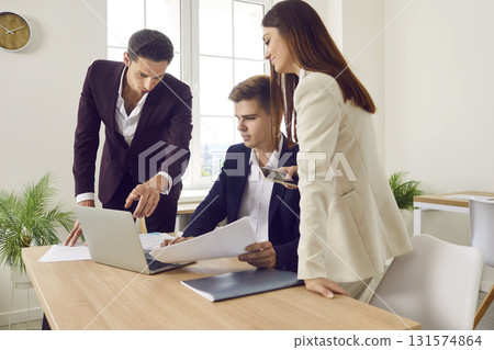 Young smart friendly coworkers in office are discussing fulfillment of company's business tasks. 131574864