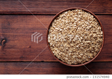 Raw Whole Oats in Ceramic Bowl on Dark Wood Background Top View Copy Space 131574940