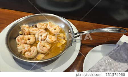 Delicious sauteed shrimp in garlic butter sauce served in a skillet on wooden table. Spanish tapas. Bar in Madrid. Traditional Spanish dish Delicious sauteed shrimp in garlic butter sauce served in a skillet on wooden table. Spanish tapas. Bar in Madrid. Traditional Spanish dish 131574960
