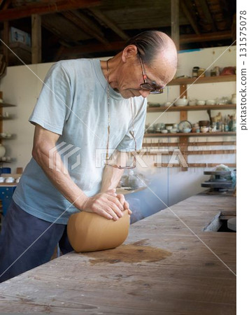 資深陶藝家在陶藝工作坊裡揉捏陶土 131575078