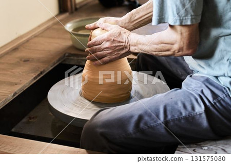 A potter using a potter's wheel to shape a vessel A potter using a potter's wheel to shape a vessel 131575080