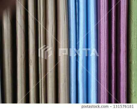Elegant fabric curtain display in muted brown, sky blue, plum and sage green with subtle texture and soft folds evoking calm and refined atmosphere 131576181
