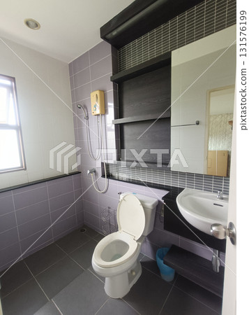 Modern bathroom interior with open toilet seat, wall shower, sink and shelving creating clean functional space with soft light and muted tile tones Modern bathroom interior with open toilet seat, wall shower, sink and shelving creating clean functional space with soft light and muted tile tones 131576199