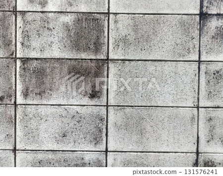 Weathered concrete block wall with mold stains and grid pattern conveying urban decay and texture 131576241