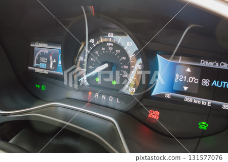 Car dashboard with headlights fog lights and hazard lights on while parked with handbrake 131577076