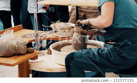 A potter shaping clay on a pottery wheel during a public workshop at a local artisanal fair, demonstrating handmade ceramics process and pottery techniques A potter shaping clay on a pottery wheel during a public workshop at a local artisanal fair, demonstrating handmade ceramics process and pottery techniques 131577155