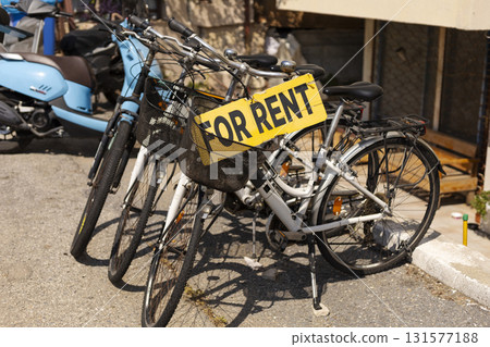 Several bicycles are lined up for rent in a bustling urban spot. The scene shows sunny weather, ideal for cycling around the city and enjoying the outdoors Several bicycles are lined up for rent in a bustling urban spot. The scene shows sunny weather, ideal for cycling around the city and enjoying the outdoors 131577188