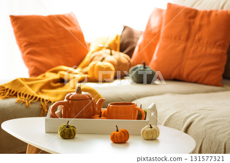 Autumnal living room decor with pumpkins, teapot, tea cup and cozy blankets. Autumnal living room decor with pumpkins, teapot, tea cup and cozy blankets. 131577321