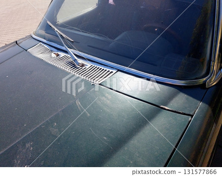 Old Dark Green Car Parked in a Quiet Area on a Sunny Day Capturing Nostalgia and Vintage Charm 131577866