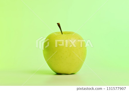 A green apple sits on a light green background 131577907