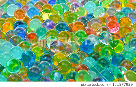 A bunch of colorful marbles are scattered on a surface 131577929