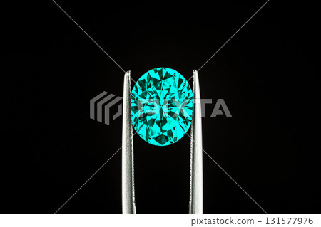 A close up of a paraiba tourmaline in jewelry tweezers 131577976