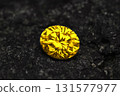A yellow diamond is sitting on a black rock 131577977