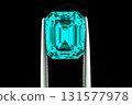 A blue gemstone is being held up by a metal tool 131577978